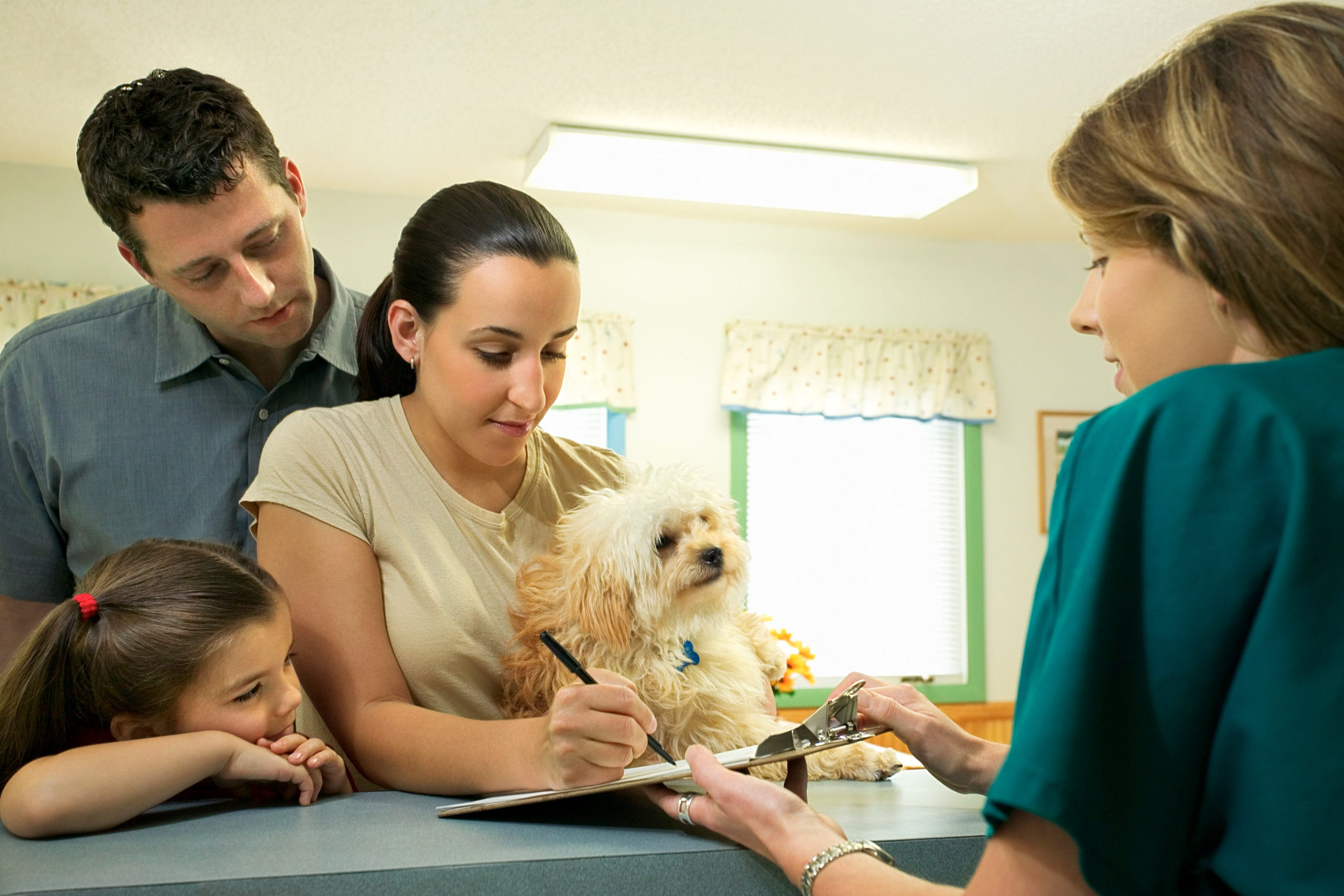 Family with dog filling out paperwork at vet clinic