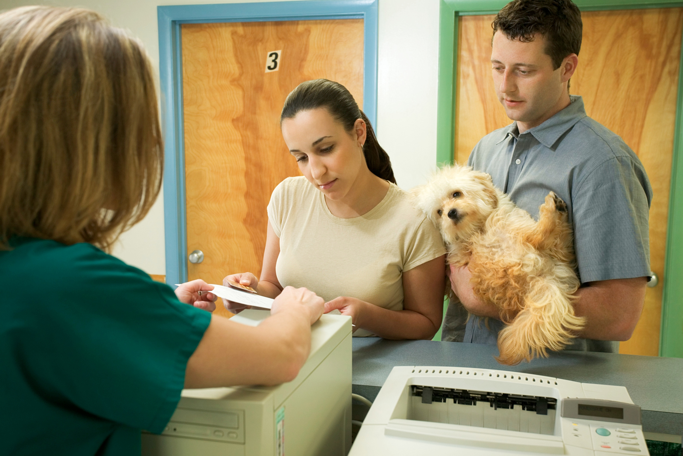 Couple with dog at front desk of vet clinic